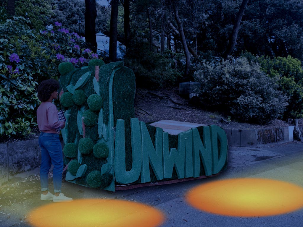 A huge seating structure in 
		Bournemouth Gardens Woods with the word unwind on it, at night with a light
		projection beside it